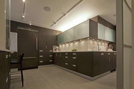 Kitchen with dark cabinetry, frosted-glass upper cabinets, under-cabinet lighting and track lights