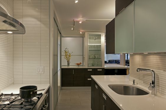 Kitchen with frosted-glass upper cabinets, dark lower cabinets, a white countertop and an undermount sink