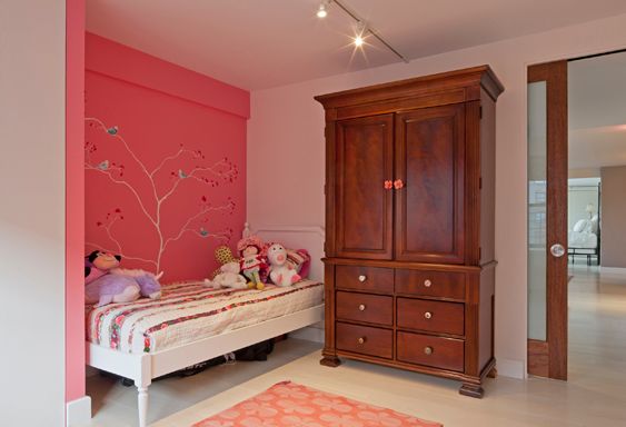 Bedroom with a coral accent wall painted with a branch motif, a white daybed and a wooden armoire
